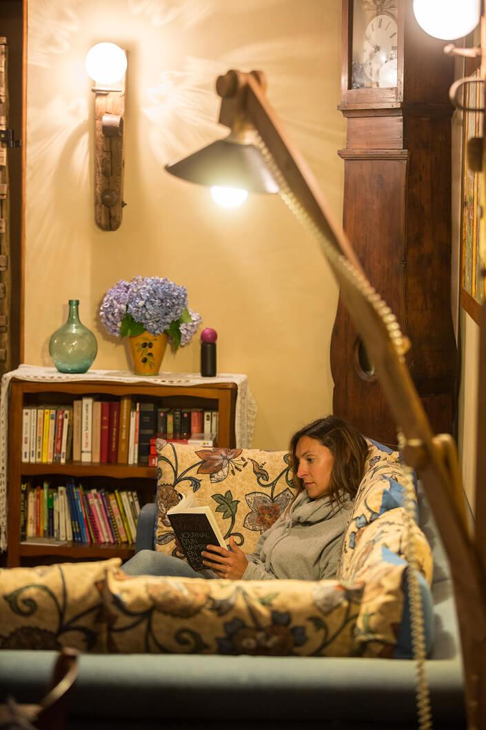 Une femmes assise dans un canapé lisant un livre