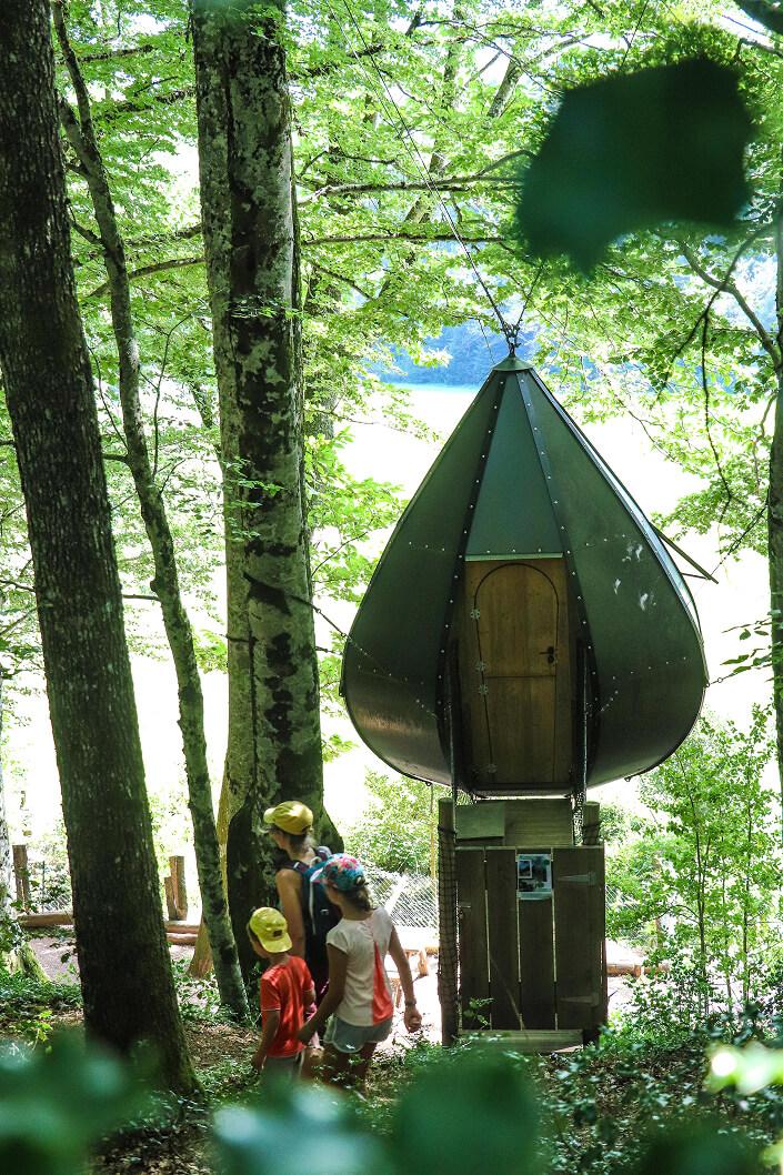 Structure métallique en fôret, trois personnes passent devant